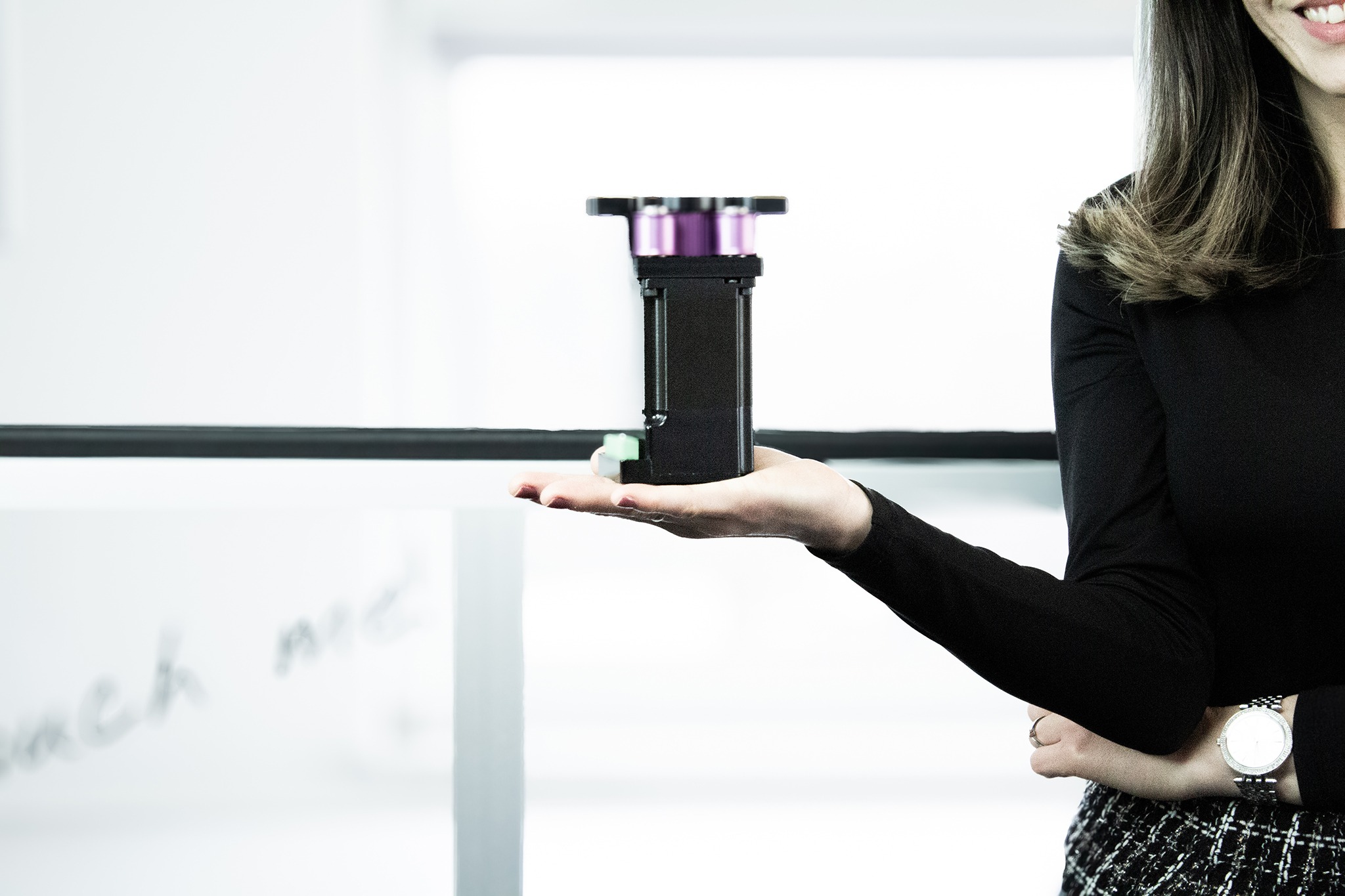 Mitarbeiterin hält energieeffizienten Direktantrieb für eine Hubtür, im Hintergrund eine remonic® MagicGate im Einsatz