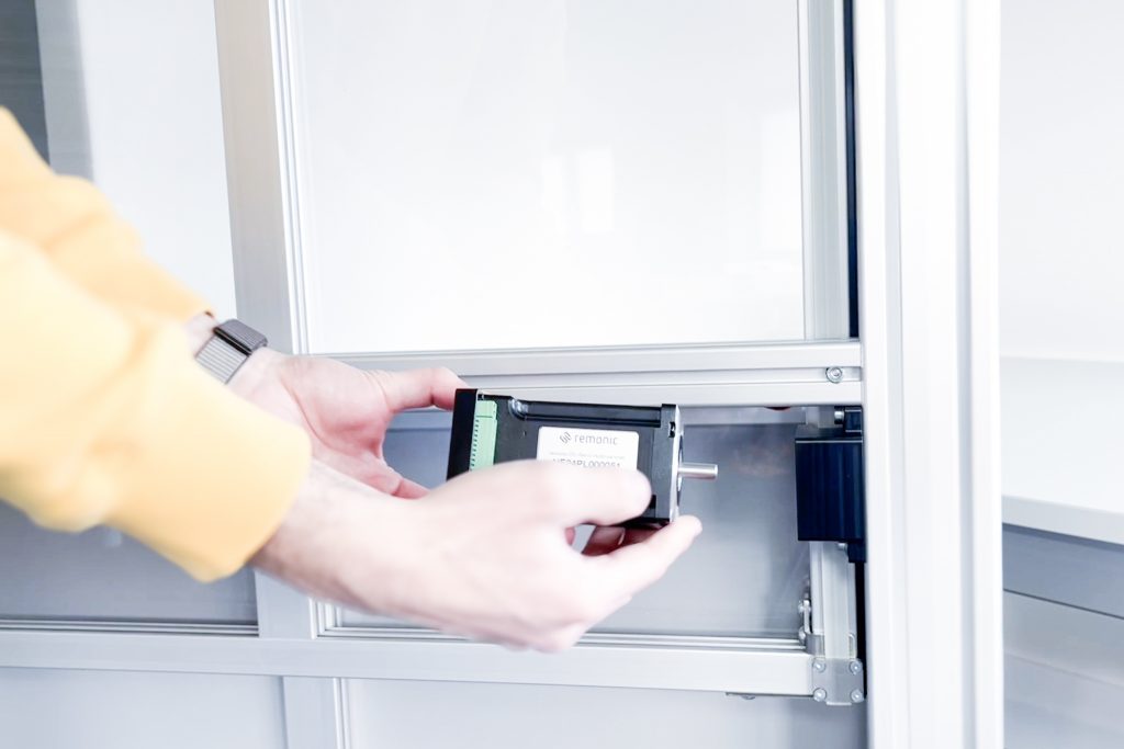 Mitarbeiter hält demontierte Motorsteuereinheit einer remonic® Hubtür beim Motortausch in der Hand