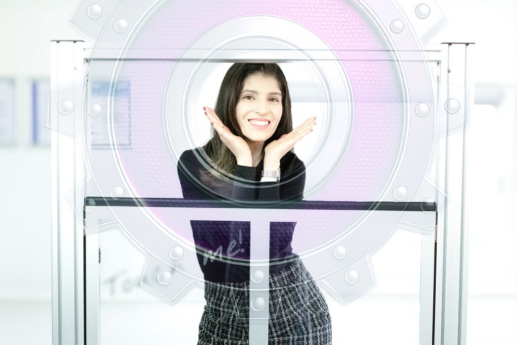 Mitarbeiterin hält ein stilisiertes Zahnrad als Symbol für die technischen Daten der remonic® Hubtürsysteme, im Hintergrund eine industrielle Hubtür.